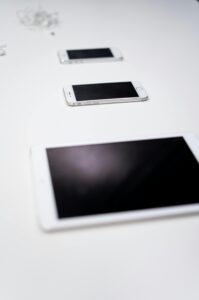 A minimalist arrangement of Apple gadgets including a tablet and smartphones on a white surface.